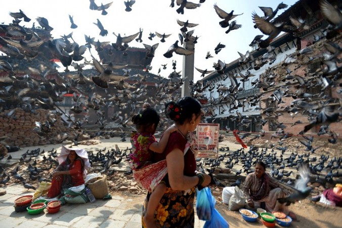 Flying pigeons pass over Nepalese street vendors near the earthquake damaged UNESCO World Heritage Site, Durbar Square in Kathmandu on May 20, 2015. Nearly 8,500 people have now been confirmed dead in the disaster, which destroyed more than half a million homes and left huge numbers of people without shelter with just weeks to go until the monsoon rains. AFP PHOTO / ISHARA S. KODIKARA / AFP PHOTO / Ishara S.KODIKARA